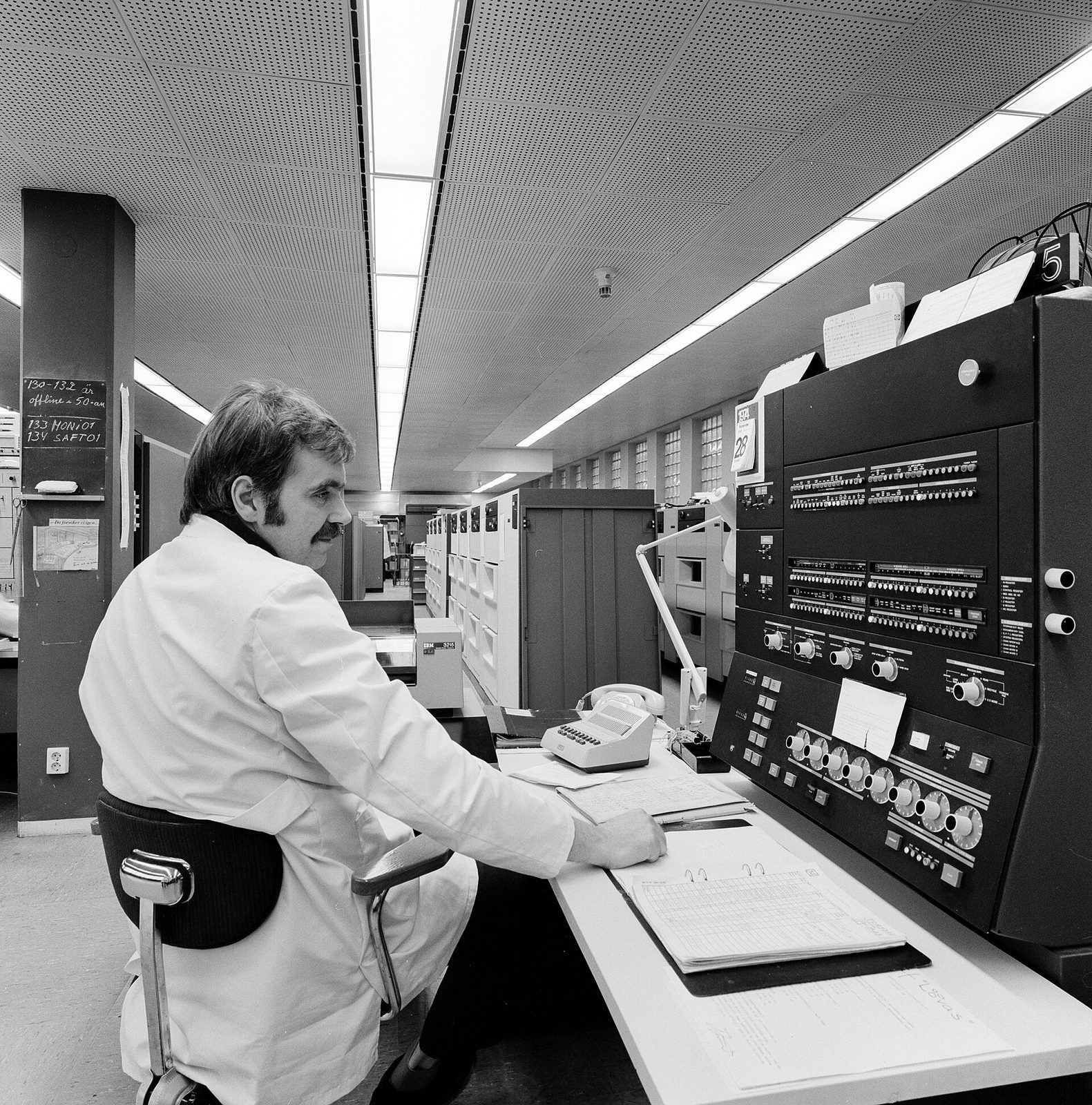 Operátor v bílém plášti u konzole IBM 370/145 s obrazovkou a klávesnicí