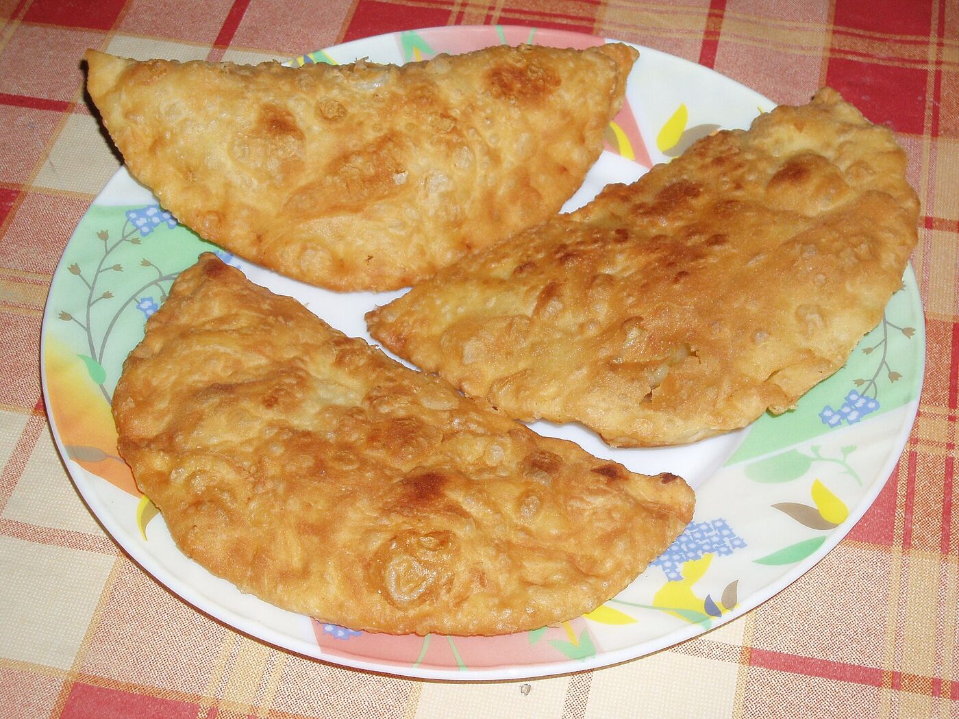 Tři smažené čebureky na talíři, zlaté s puchýřky