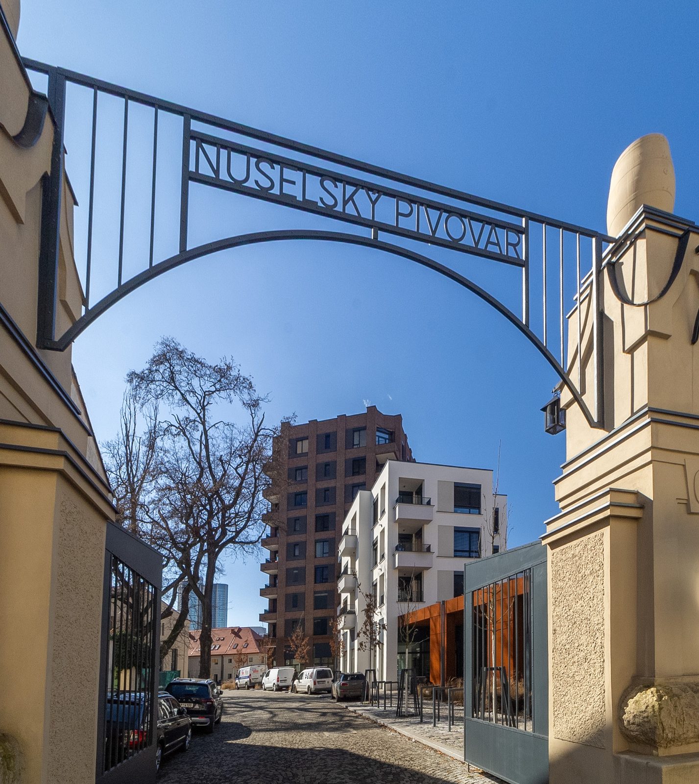 Nová brána s nápisem Nuselský pivovar, za ní rezidenční novostavby